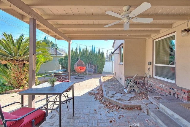 view of patio with outdoor dining area, fence, and ceiling fan