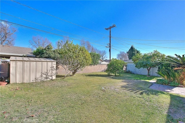 view of yard featuring an outbuilding, a fenced backyard, and a storage shed