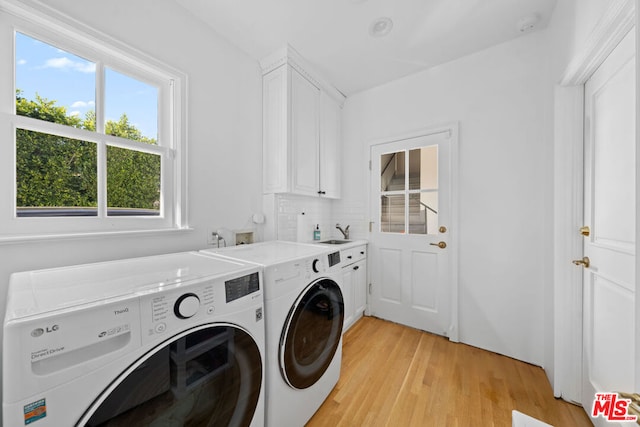 laundry room with cabinets, washer and clothes dryer, plenty of natural light, and light wood-type flooring