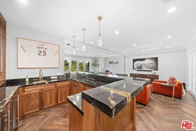 kitchen featuring a kitchen island, decorative light fixtures, dark stone counters, sink, and parquet floors