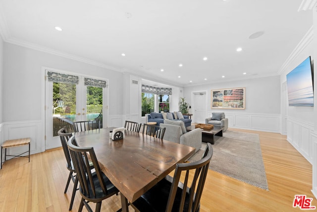 dining room featuring light wood-type flooring, ornamental molding, and french doors