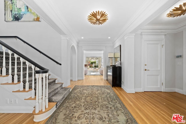 foyer entrance with light wood-type flooring and ornamental molding