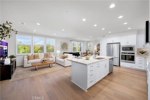 kitchen featuring an island with sink, white cabinets, sink, and stainless steel appliances