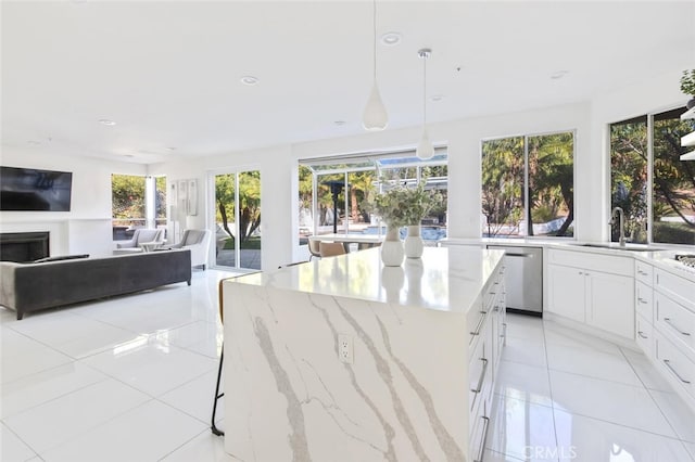 kitchen with sink, light tile patterned floors, dishwasher, white cabinetry, and hanging light fixtures