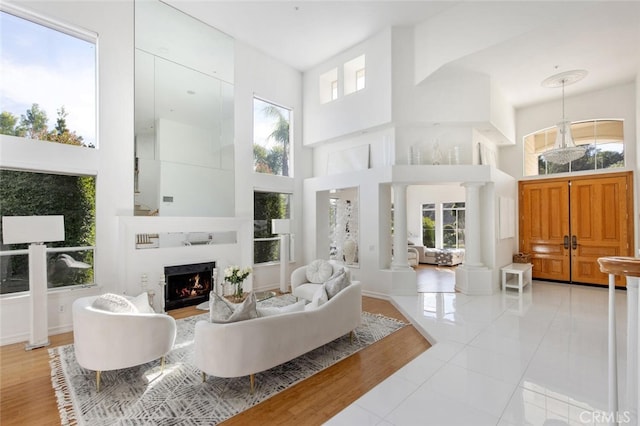 living room with light tile patterned floors, decorative columns, and a high ceiling