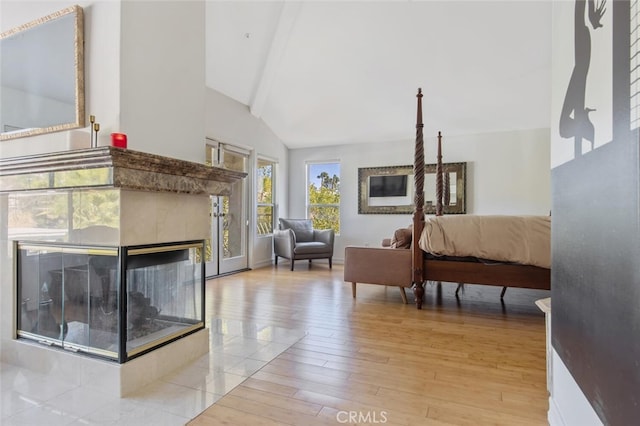 bedroom featuring lofted ceiling with beams, access to outside, a fireplace, and light hardwood / wood-style floors