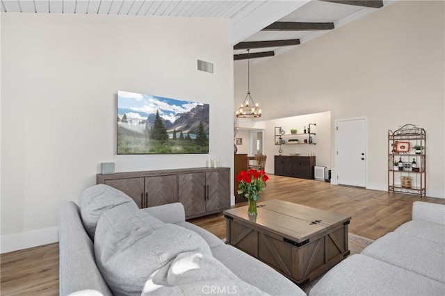 living room featuring hardwood / wood-style flooring, high vaulted ceiling, beam ceiling, and an inviting chandelier