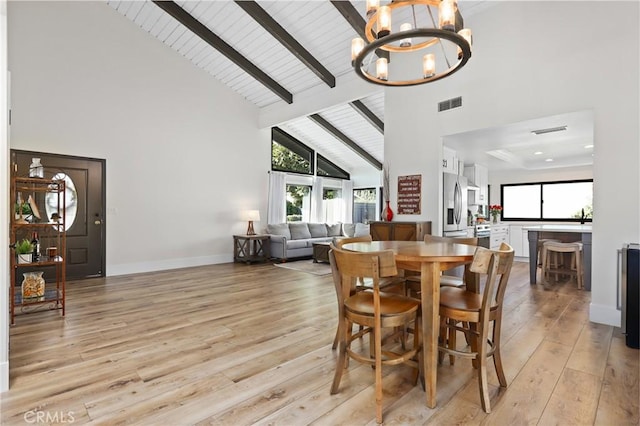 dining space with light wood-type flooring, an inviting chandelier, and high vaulted ceiling