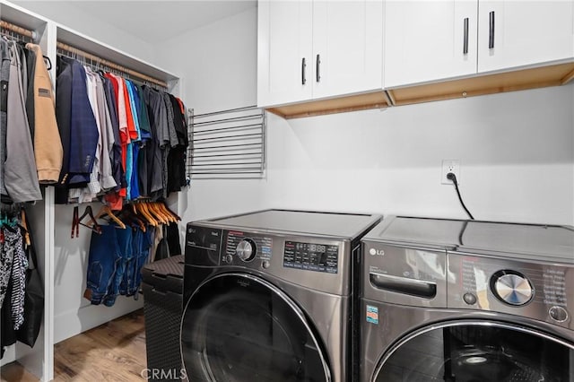 clothes washing area featuring cabinets, separate washer and dryer, and wood-type flooring