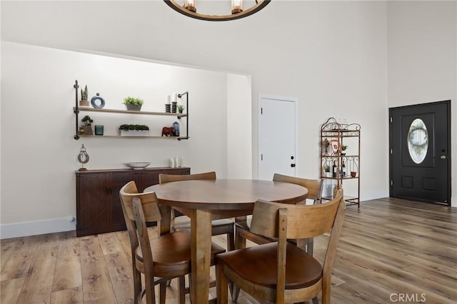 dining room featuring an inviting chandelier, a high ceiling, and light hardwood / wood-style flooring