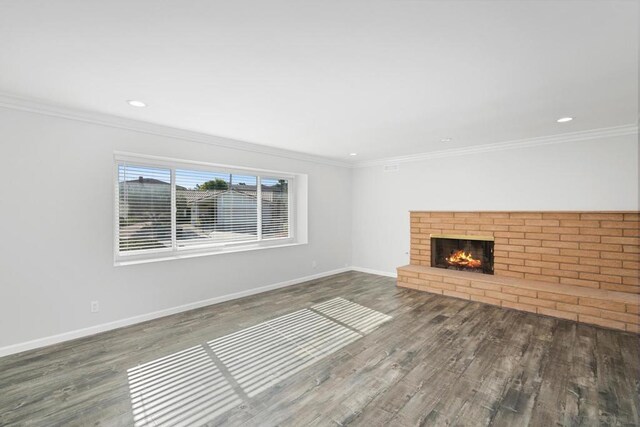 unfurnished living room with wood-type flooring, ornamental molding, and a fireplace