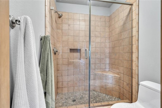 bathroom featuring a shower with shower door and toilet