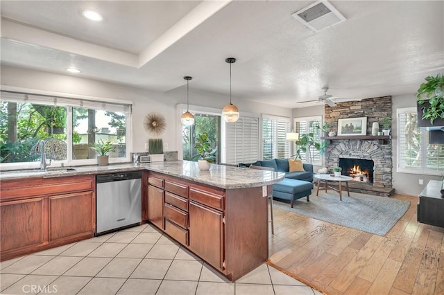 kitchen with pendant lighting, dishwasher, a fireplace, sink, and kitchen peninsula