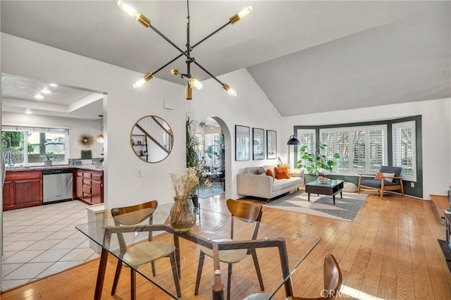 dining space with lofted ceiling, a notable chandelier, and light hardwood / wood-style floors