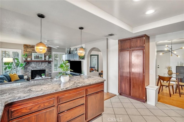 kitchen featuring decorative light fixtures, light stone counters, light tile patterned floors, and a fireplace