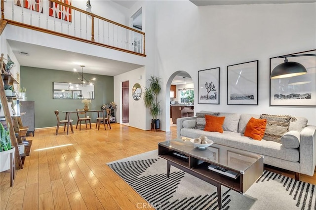 living room with a chandelier, wood-type flooring, and a towering ceiling