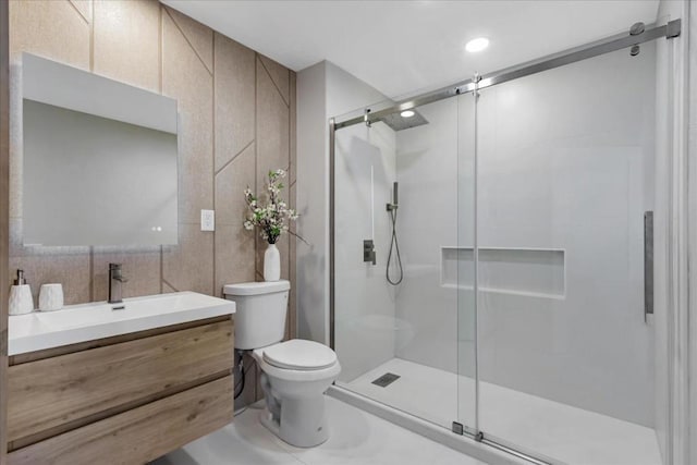 bathroom featuring a shower with door, tile walls, toilet, and vanity