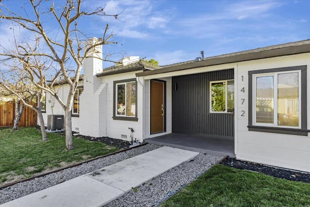 property entrance featuring cooling unit and a lawn