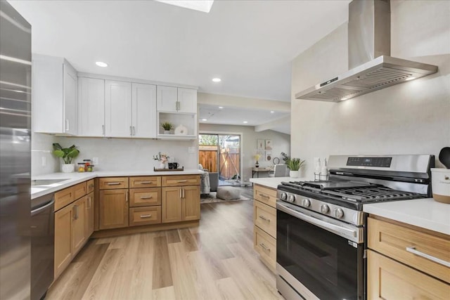 kitchen featuring white cabinetry, light hardwood / wood-style flooring, appliances with stainless steel finishes, light brown cabinets, and wall chimney exhaust hood