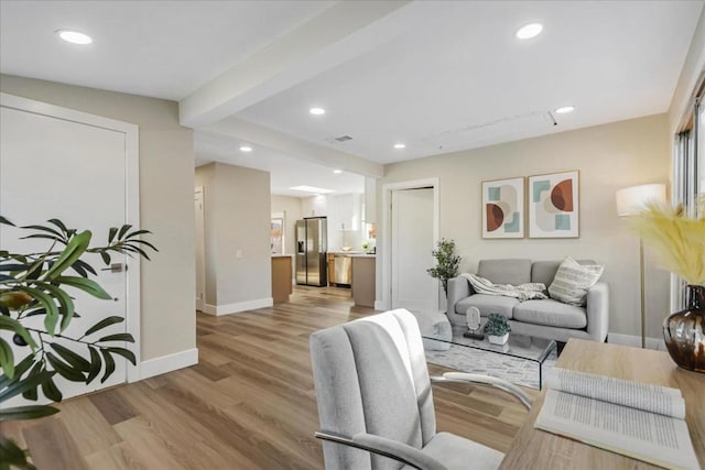 living room featuring beam ceiling and light hardwood / wood-style floors