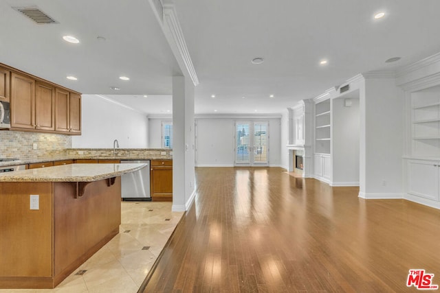 kitchen featuring french doors, light stone counters, stainless steel dishwasher, crown molding, and a breakfast bar