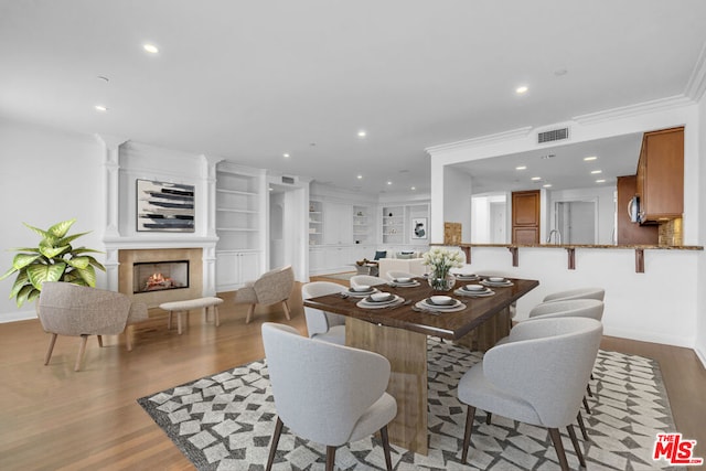 dining space with light hardwood / wood-style floors and ornamental molding