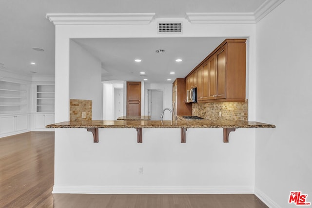 kitchen with light stone countertops, a kitchen bar, and kitchen peninsula