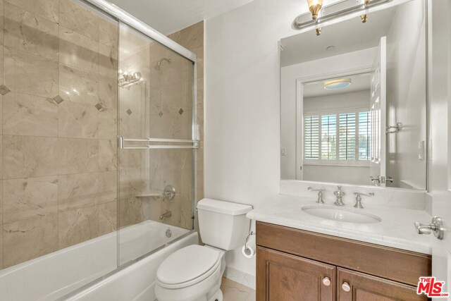 full bathroom featuring vanity, bath / shower combo with glass door, and toilet