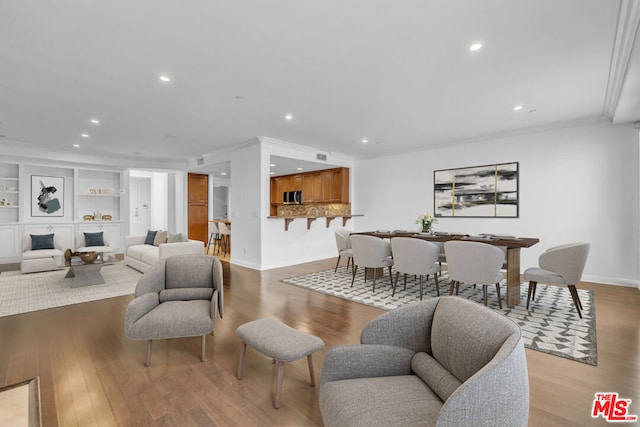 living room with light hardwood / wood-style floors, built in features, and crown molding