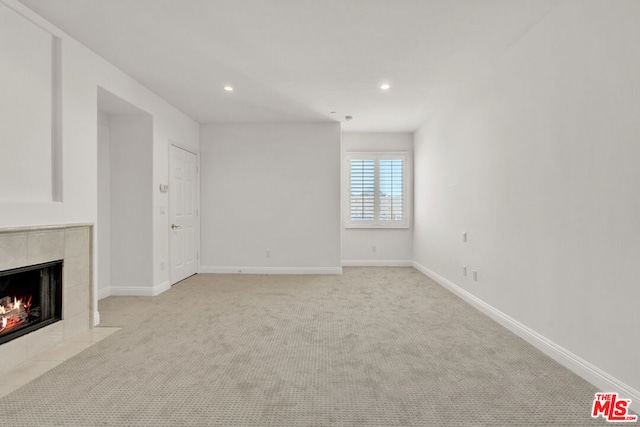 unfurnished living room featuring light colored carpet and a tiled fireplace