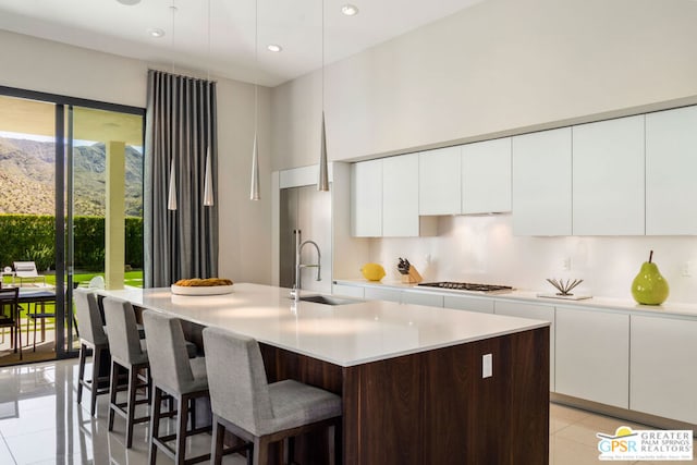 kitchen featuring sink, a mountain view, an island with sink, a breakfast bar area, and white cabinets