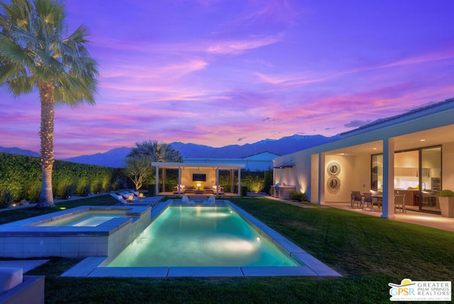 pool at dusk with a mountain view, a yard, outdoor lounge area, an in ground hot tub, and a patio