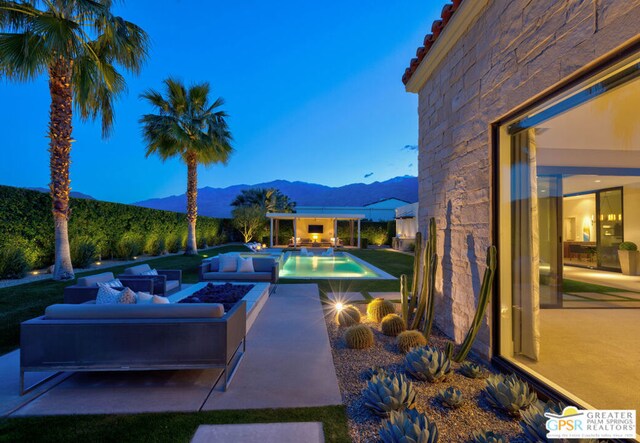 pool at dusk featuring a patio area, a mountain view, and an outdoor fire pit