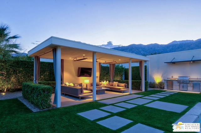 rear view of house with an outdoor kitchen, a patio, ceiling fan, a yard, and an outdoor living space