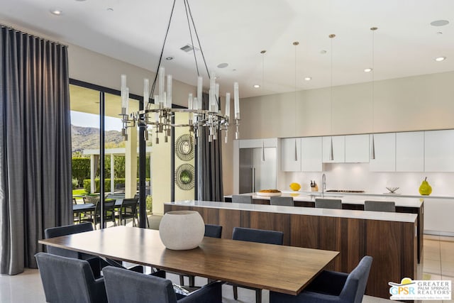 dining area featuring light tile patterned flooring, a mountain view, a high ceiling, and sink