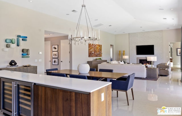 kitchen with a fireplace, a kitchen island, hanging light fixtures, light tile patterned floors, and beverage cooler