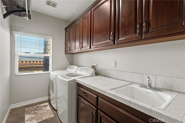 laundry room featuring washer and clothes dryer, dark tile patterned flooring, sink, and cabinets