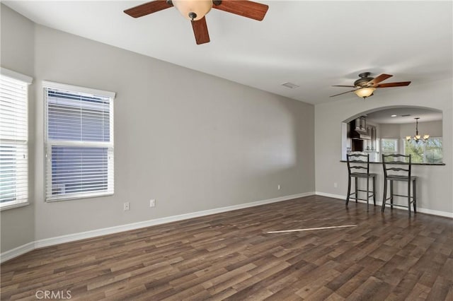 empty room with a healthy amount of sunlight, dark wood-type flooring, and a chandelier