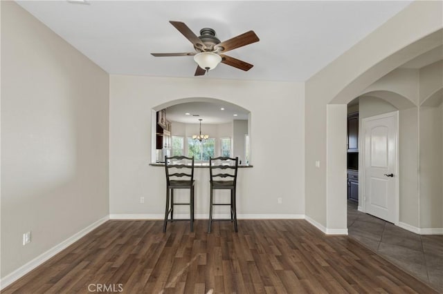 unfurnished dining area with ceiling fan with notable chandelier and dark hardwood / wood-style flooring