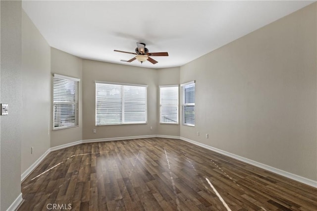 spare room featuring ceiling fan, dark wood-type flooring, and plenty of natural light