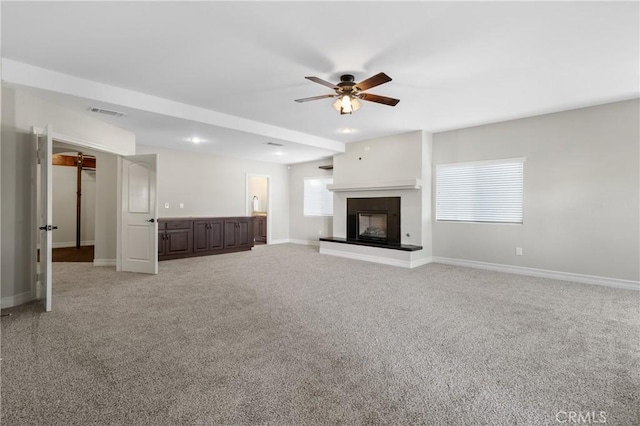 unfurnished living room with ceiling fan and carpet