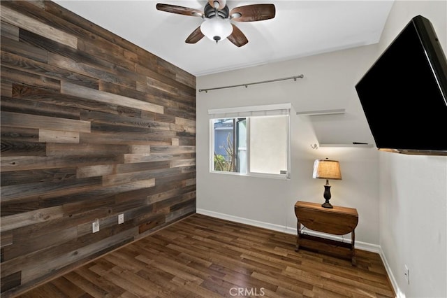 empty room with ceiling fan, dark hardwood / wood-style flooring, and wood walls