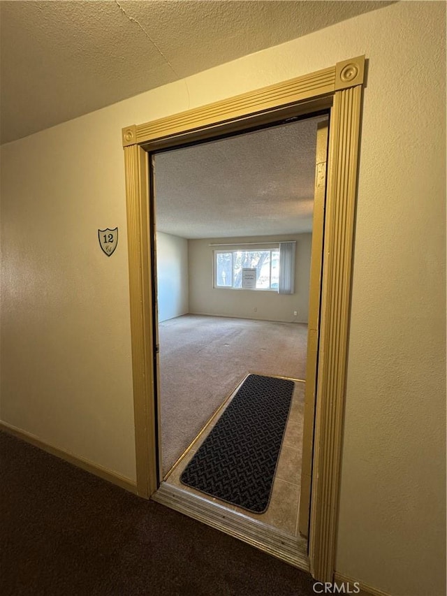 hall with carpet floors and a textured ceiling