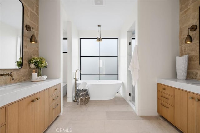 bathroom with a tub to relax in, vanity, and tile patterned floors