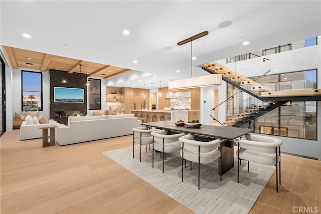 dining space with a large fireplace, wooden ceiling, stairway, light wood-style floors, and recessed lighting