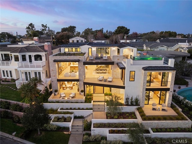 back of property with a patio, stucco siding, a standing seam roof, metal roof, and a residential view