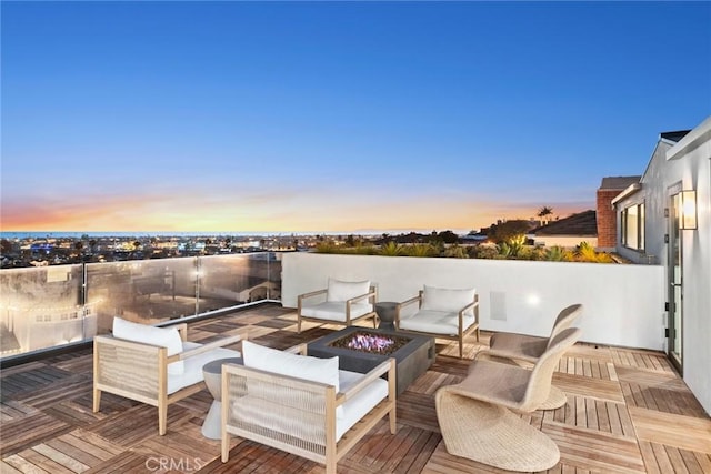 deck at dusk featuring an outdoor living space with a fire pit