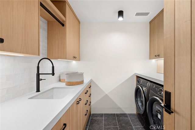 laundry area featuring dark tile patterned flooring, a sink, visible vents, independent washer and dryer, and cabinet space