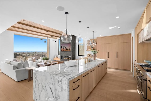 kitchen featuring a sink, a glass covered fireplace, modern cabinets, and light brown cabinets