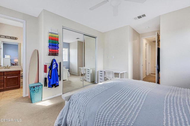 carpeted bedroom featuring ceiling fan, a closet, sink, and ensuite bathroom